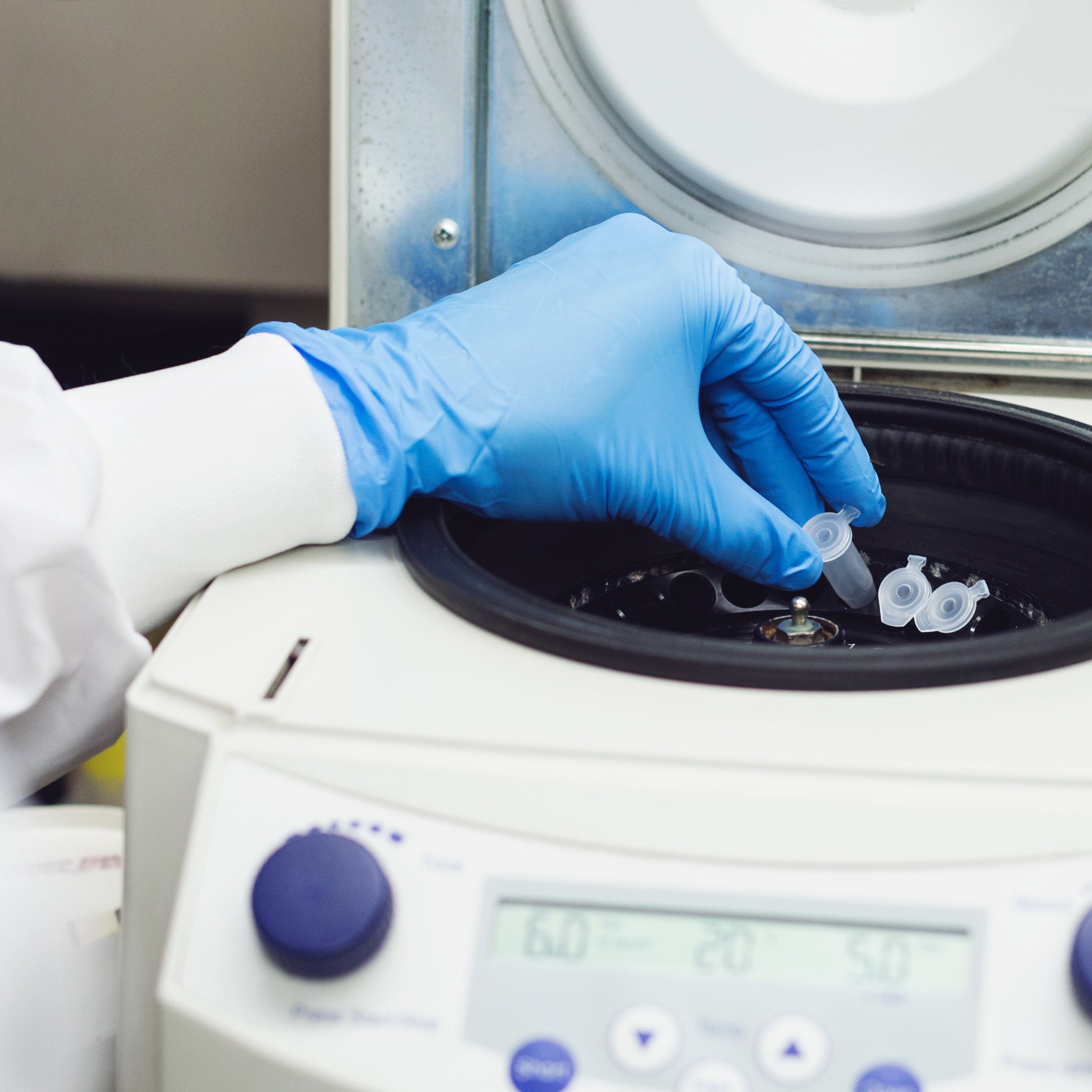 Person with blue glove using centrifuge