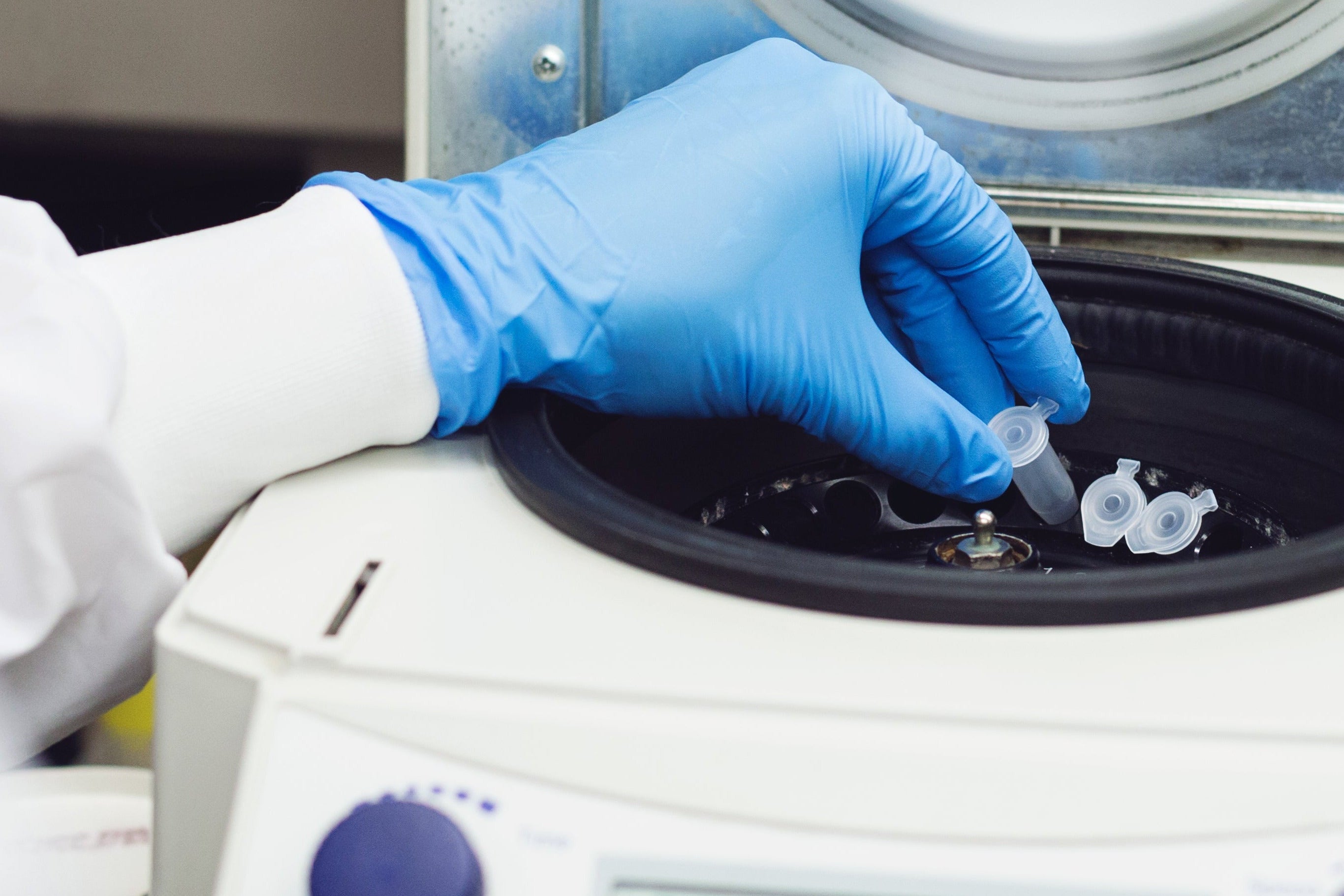 Person with blue glove using centrifuge