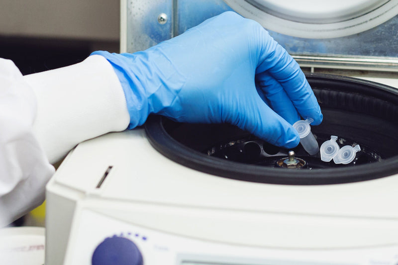 Person with blue glove using centrifuge